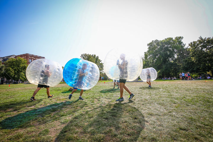 Athletes play bubble soccer on the meadow
