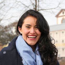 Ein Porträt von Mariana Roa Vargas. Sie lächelt breit und trägt schwarze Locken. Um ihren Hals hängt ein hellblauer Schal.