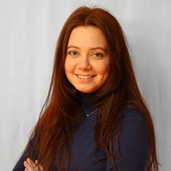Daria Shevyrev, university scout for Bachelor's degree in Business Informatics, smiles at the camera. She is wearing a dark blue sweater and has long red hair.