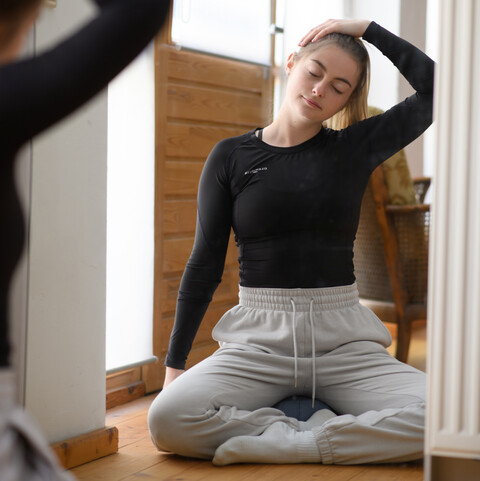 Eine studierende Person macht Yoga vor einem Spiegel.
