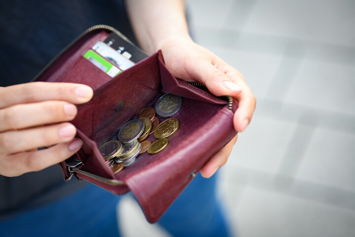 Eine Hand öffnet ein rotes Portemonnaie mit Geldmünzen