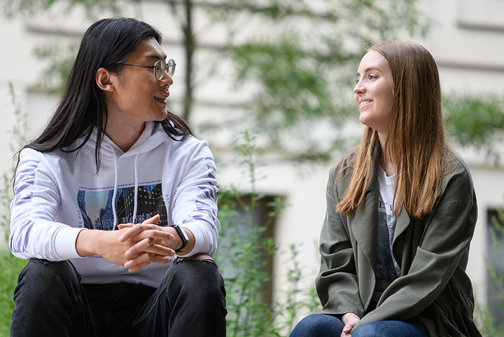 Zwei Studierende unterhalten sich draußen auf dem Campus.