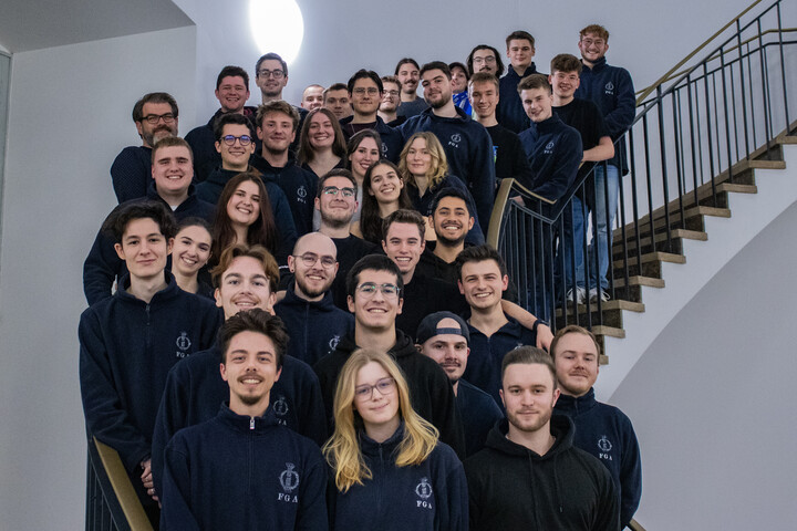 Um die 40 Mitglieder der Fachschaft Geschichte und Altertumswissenschaften stehen auf einer Treppe und lachen in die Kamera. Sie tragen einen blauen Hoodie.