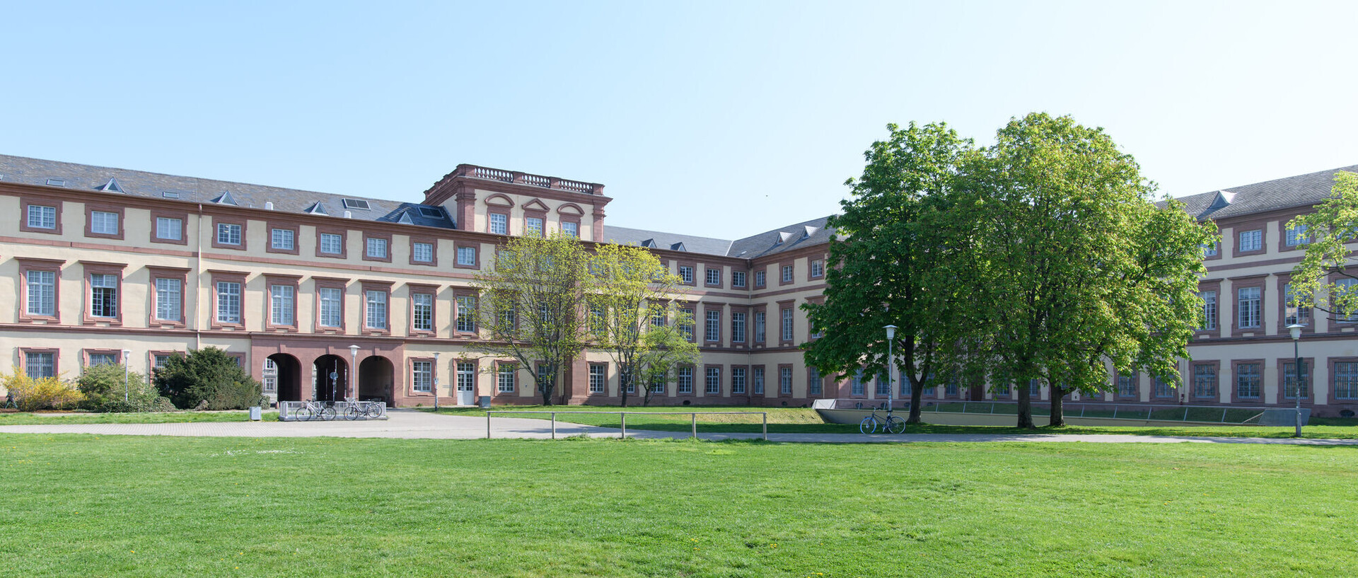 Westflügel des Schlosses der Uni Mannheim mit grünem Rasen. Link: QS-Ranking