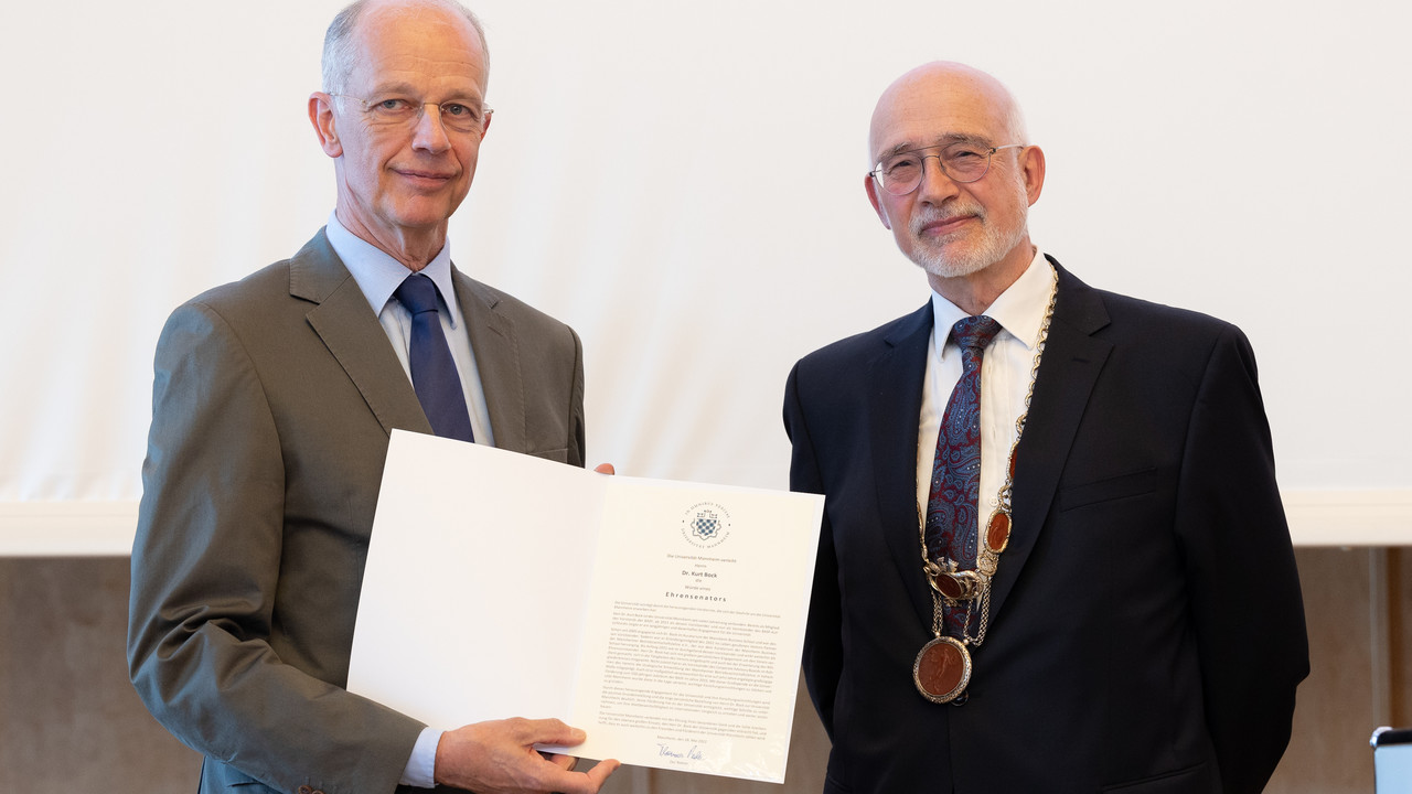 Dr. Kurt Bock hält die Urkunde zur Verleihung der Würde eines Ehrensenators in den Händen. Daneben Rektor Thomas Puhl.
