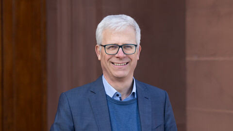 Porträtbild von Professor Eckhard Janeba. Er trägt einen Anzug und eine Brille.