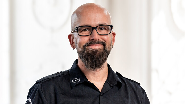 Prof. Dr. Heiko Paulheim trägt eine dunkle Brille und ein dunkles Hemd, er hat eine Glatze, einen dunklen Bart und Ohrringe.