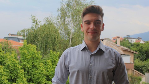 Eine Person trägt ein grau gemustertes Hemd und steht vor einem begrüntem Hintergrund. Die Person heißt Georgi Paskalev.