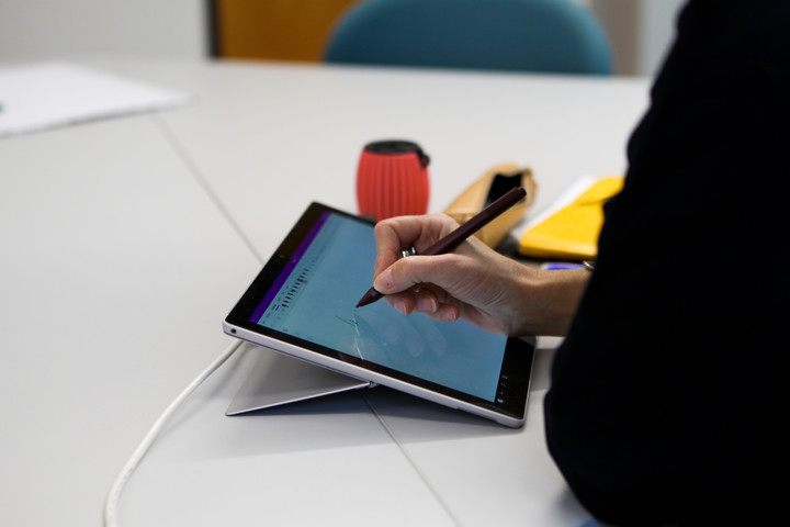 Eine Person schreibt mit einem schwarzen elektronischen Stift auf ein Tablet.