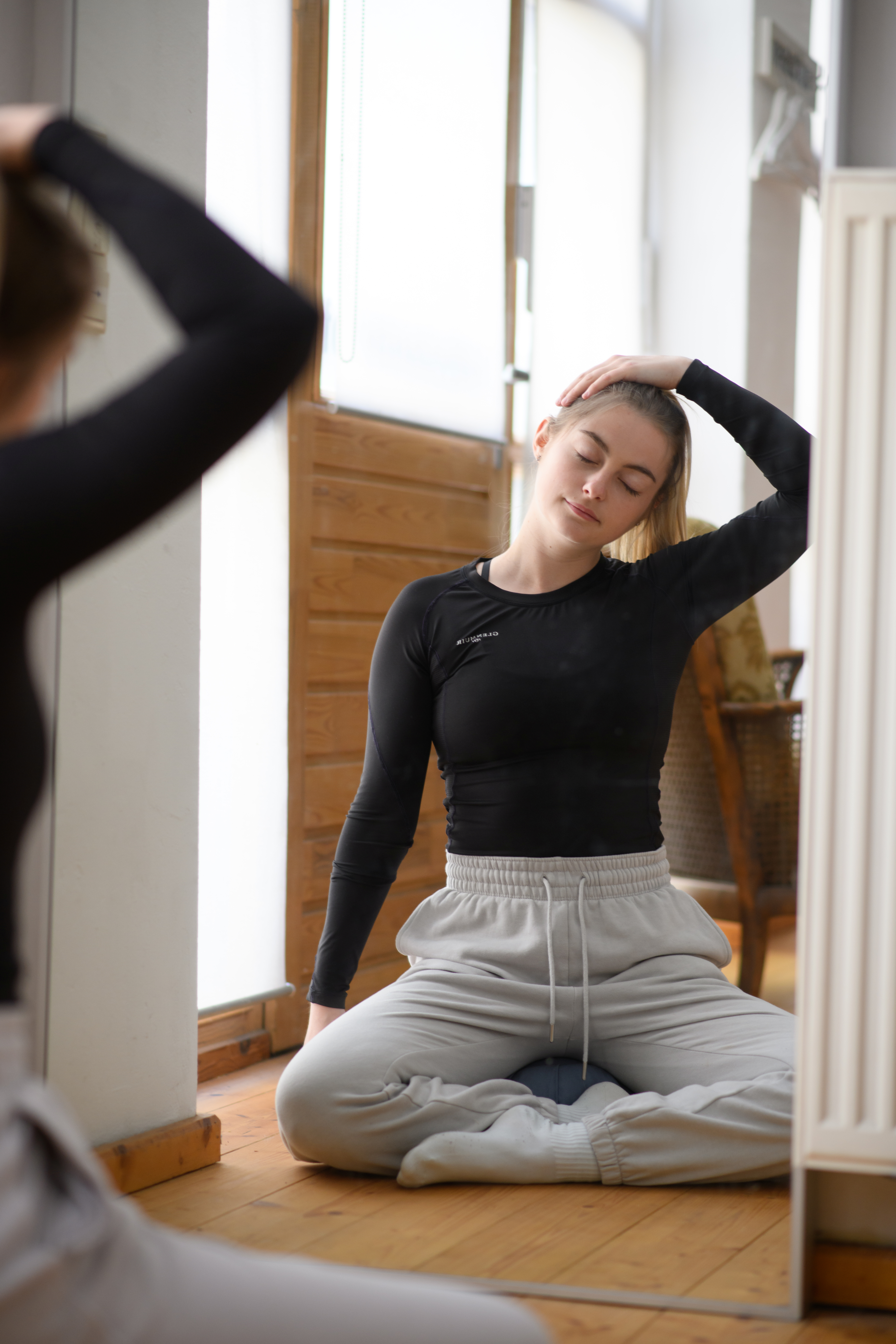 Eine studierende Person macht Yoga vor einem Spiegel.