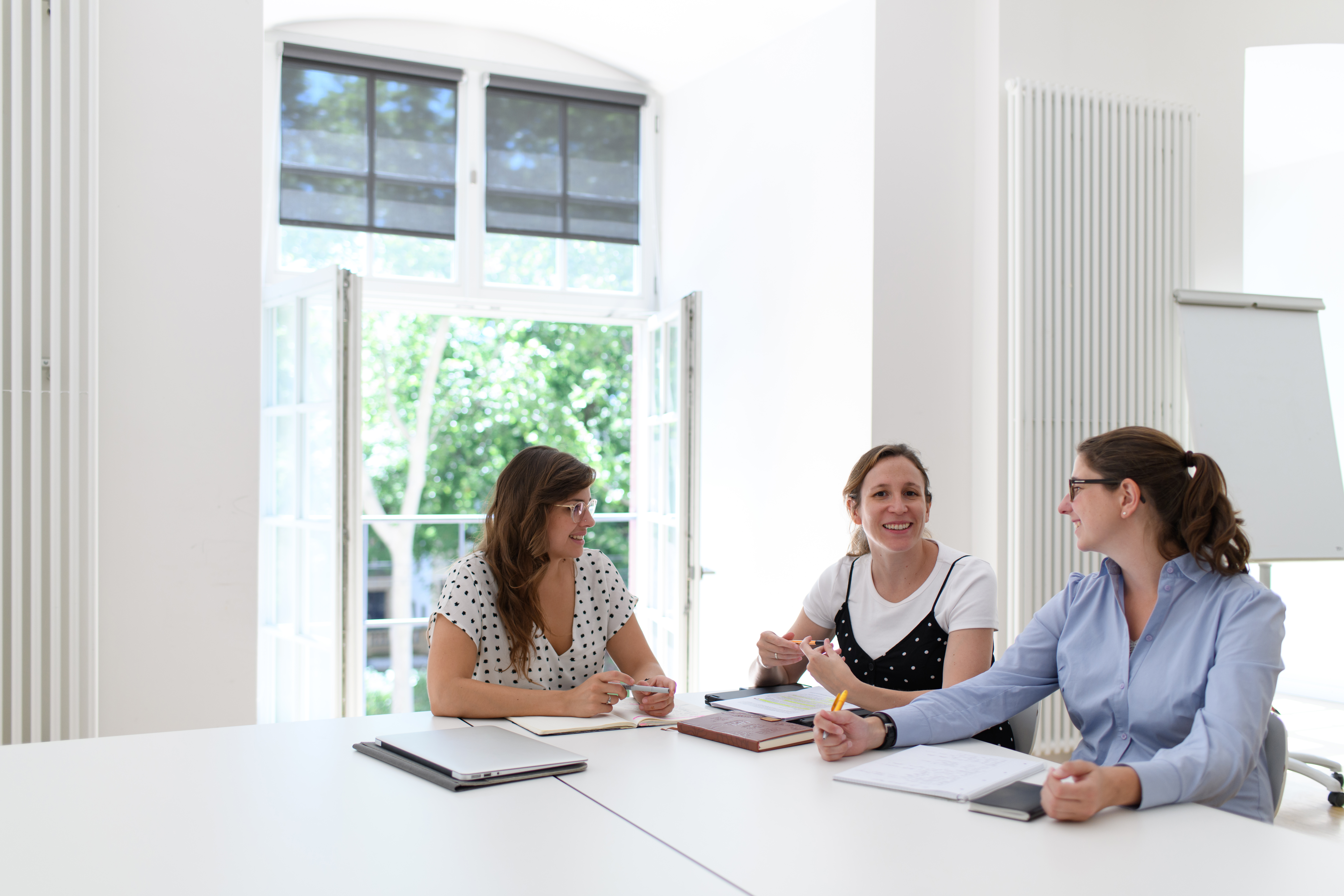 Drei Frauen sitzen in einem Seminarraum und führen ein Gespräch.