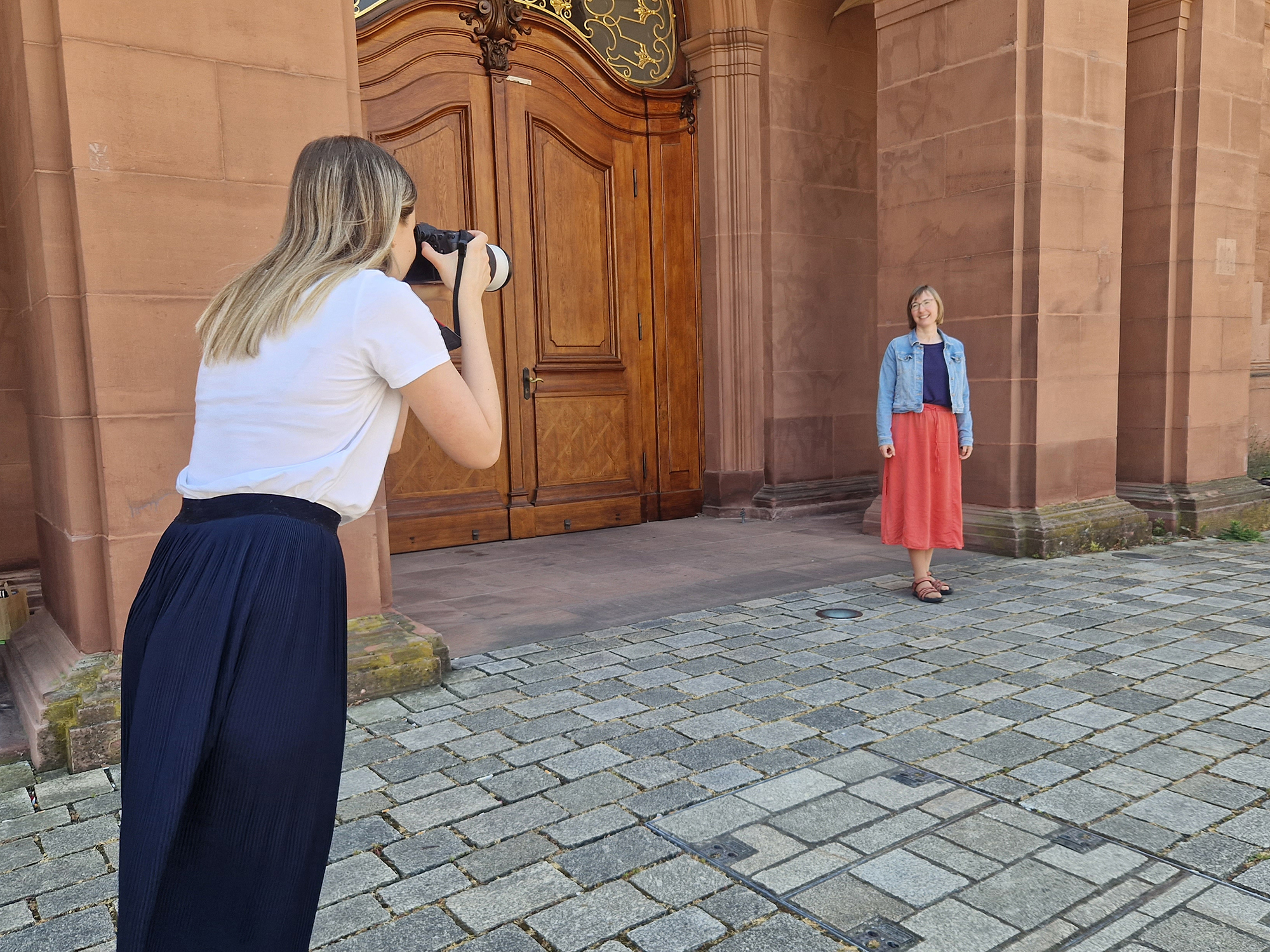 Eine Fotografin fotografiert eine Mitarbeiterin vor dem Schloss