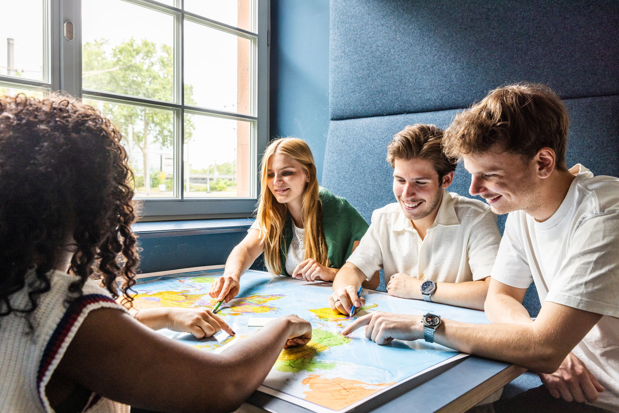 Vier Studierende an einem Arbeitsgruppentisch. Sie schauen gemeinsam auf ein Dokument. 
