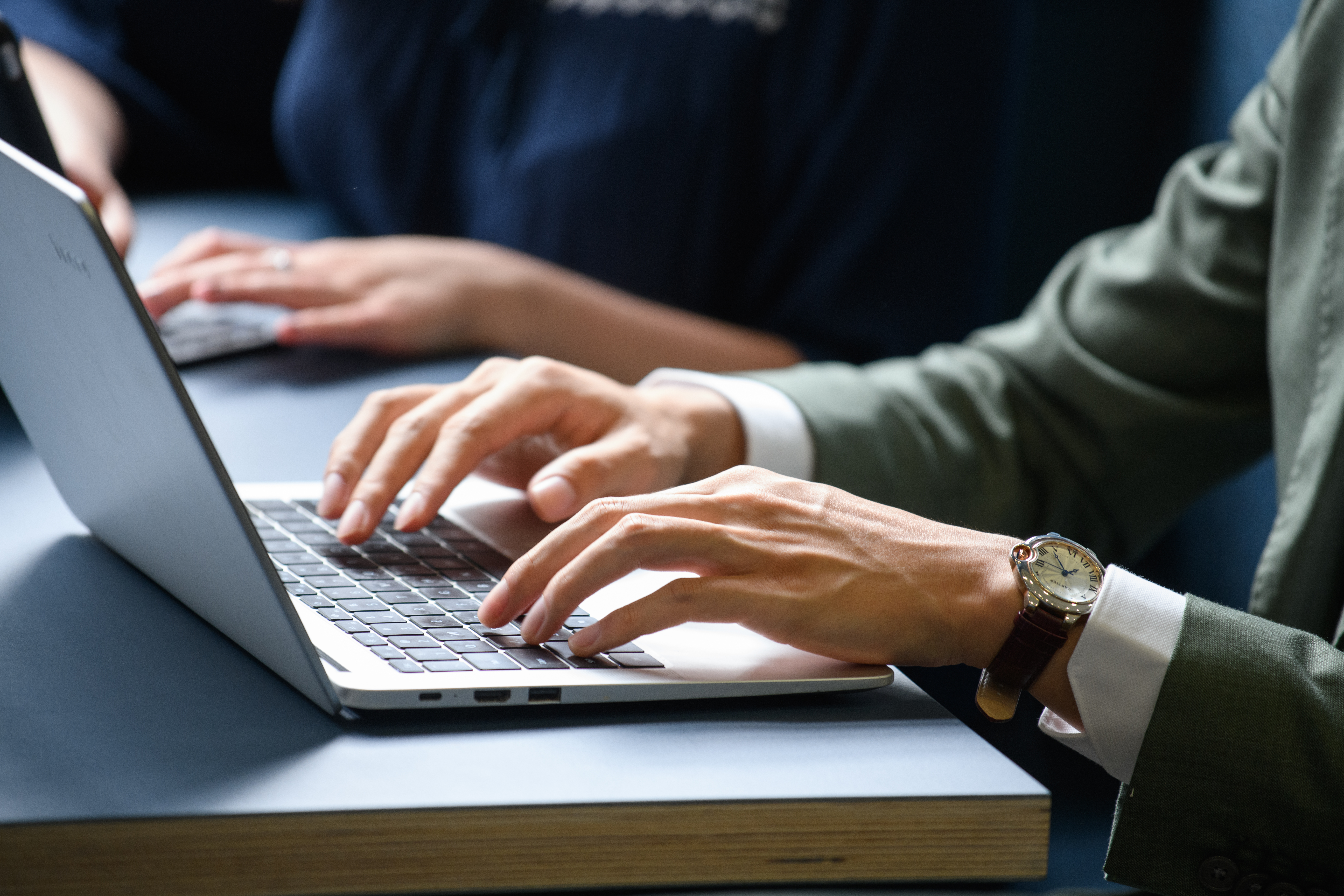 Mann im Anzug, der am Laptop arbeitet. Blick auf die Hände und das offene Laptop