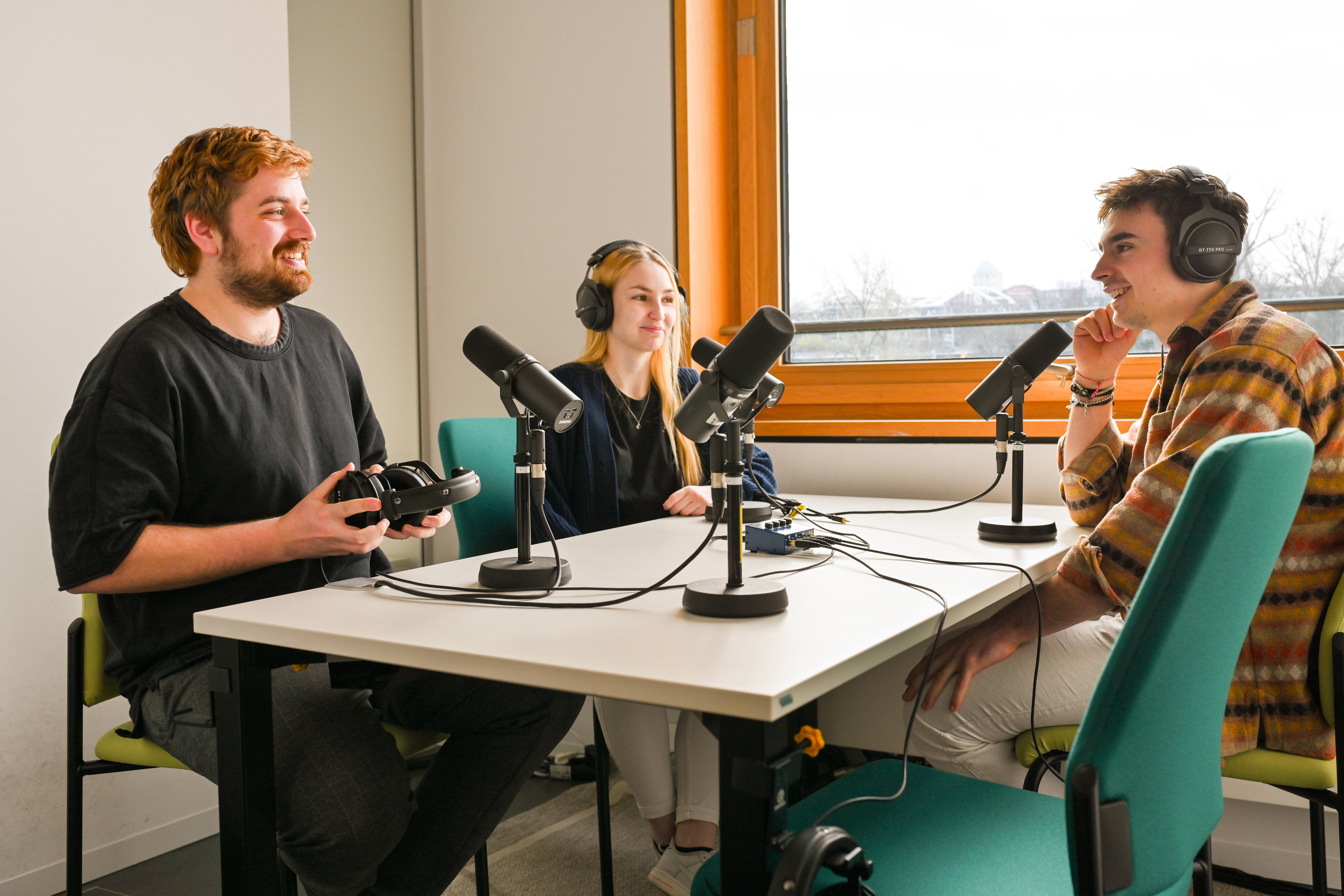 Drei Studierende zeichnen einen Podcast im Tonstudio auf.