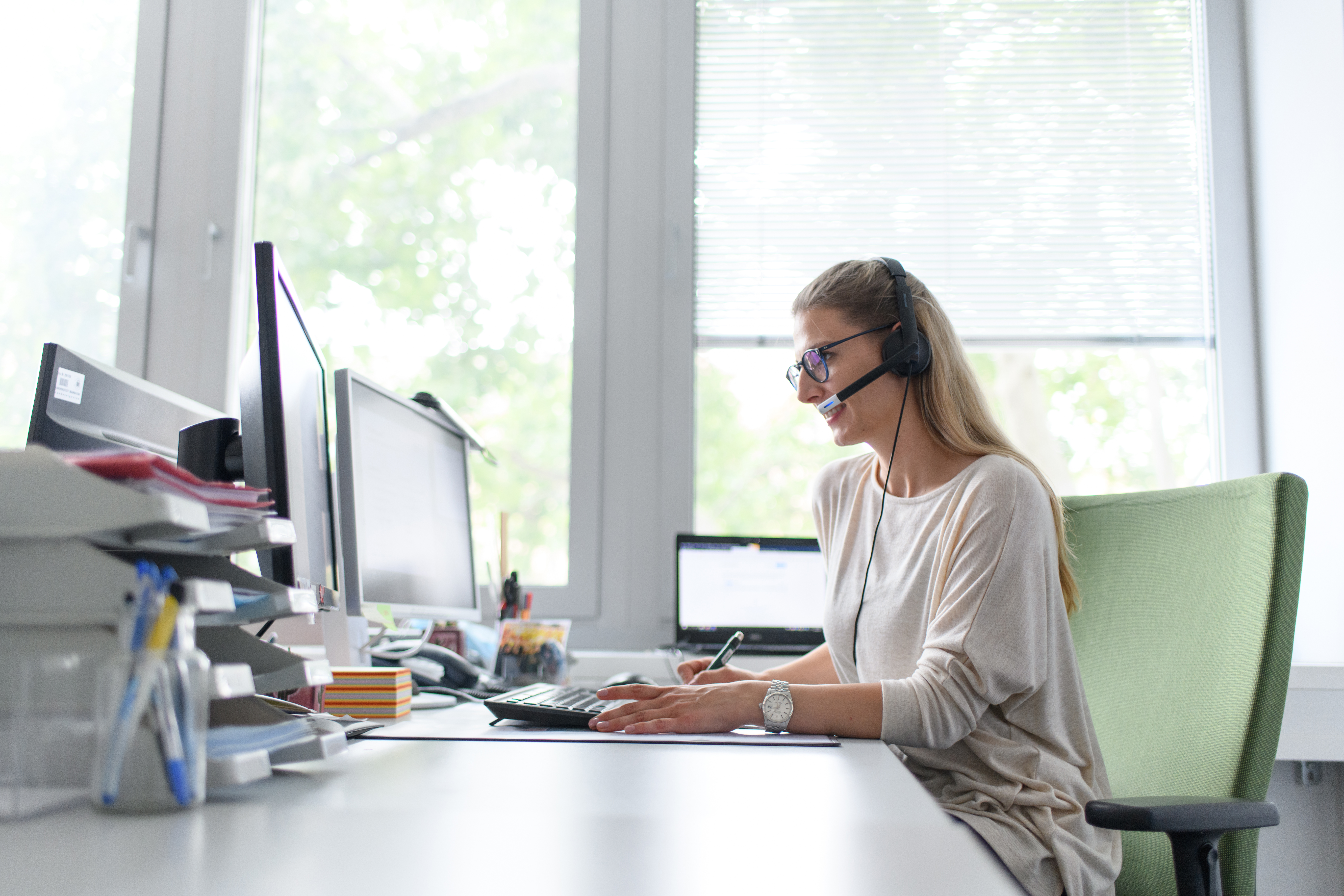 An employee with a headset is sitting in front of a computer.