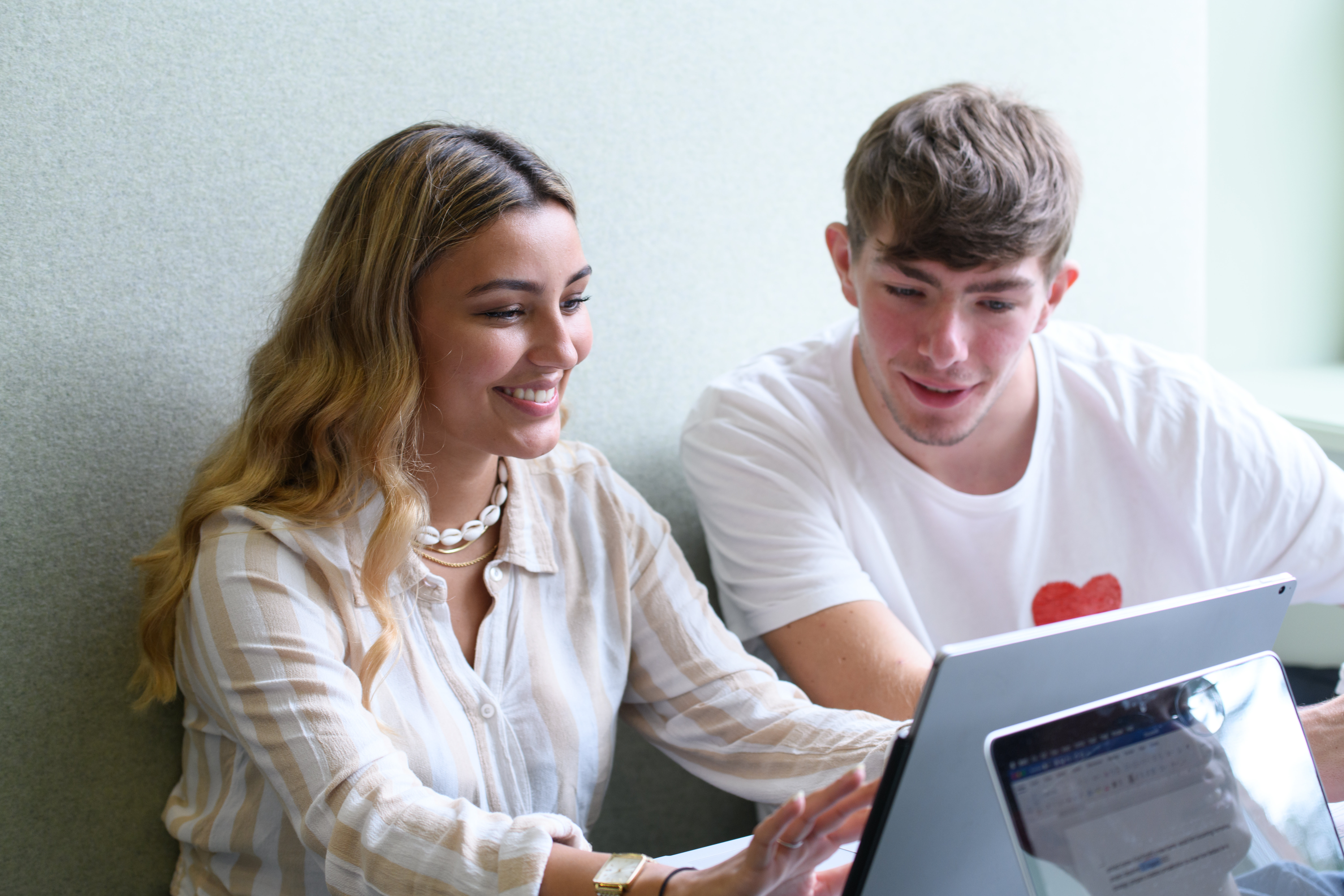 Zwei Studierende schauen auf einen Laptop.