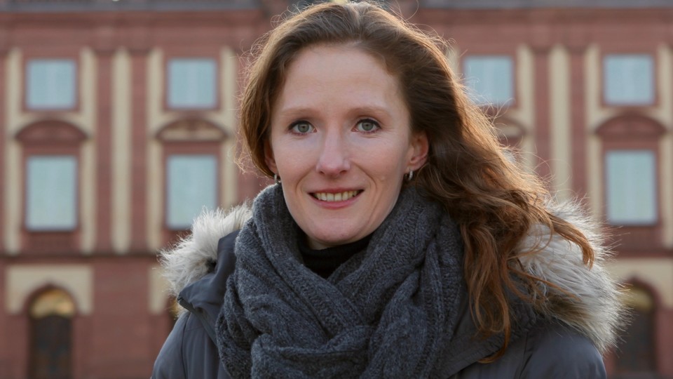 Prof. Hoisl hat lange braune Haare und steht vor dem Schloss.