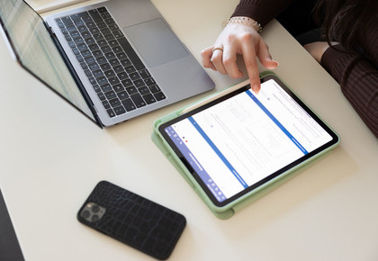 Ein von Studentin genutztes Tablet, ihr Handy und Laptop liegen auf dem Tisch
