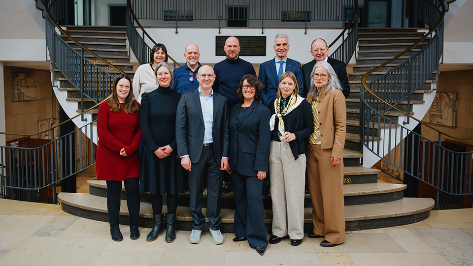 Mehrere Personen stehen vor einer Treppe und posieren für ein Foto.
