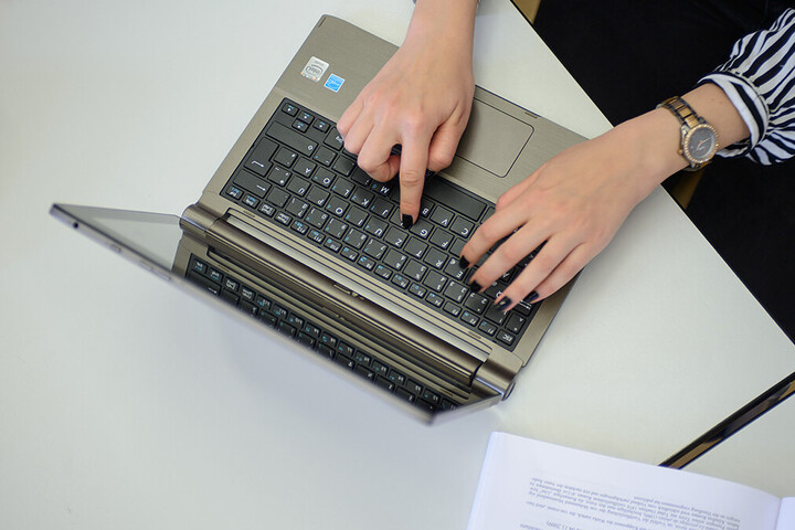 Zwei Hände tippen auf einem Laptop.