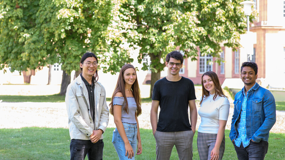 Mehrere Studierende stehen auf der Mensawiese der Universität Mannheim. 