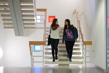 Zwei Studentinnen unterhalten sich und laufen die Treppe im Gebäude L 1 runter.