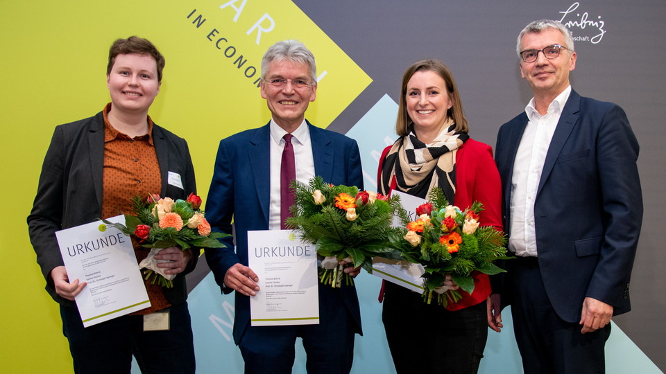 Theresa Bührle, Leonie Fischer, Christoph Spengel and another man are holding certificates and flowers.