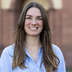 Maja Häcker is wearing a light blue blouse and a fine gold necklace with a gemstone. Her long light brown hair is worn loose. She is looking at the camera with a heartfelt smile.