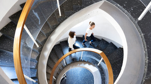 Ansicht von oben auf das Treppenhaus im Schneckenhofturm, 2 Frauen laufen die Treppe hoch.