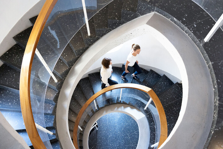 Ansicht von oben auf das Treppenhaus im Schneckenhofturm, 2 Frauen laufen die Treppe hoch. 