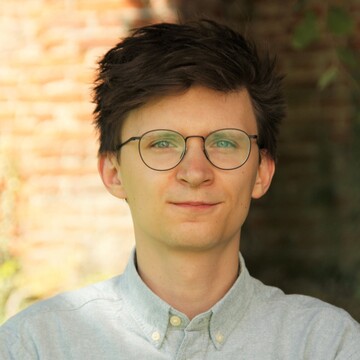 Marius Cziriak hat kurze dunkelbraune Haare. Er trägt eine Brille und ein helles Hemd.