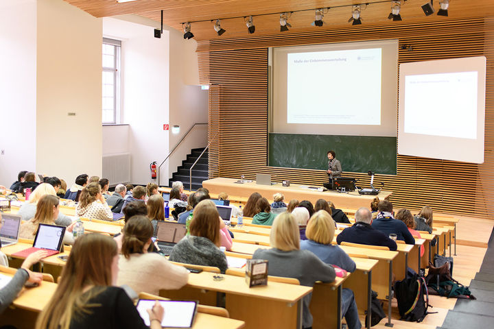 Students sit in a lecture hall and participate in a lecture.