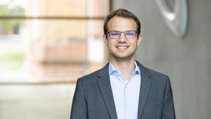Porträtbild von Professor David Prömel. Er trägt einen Anzug und eine Brille.