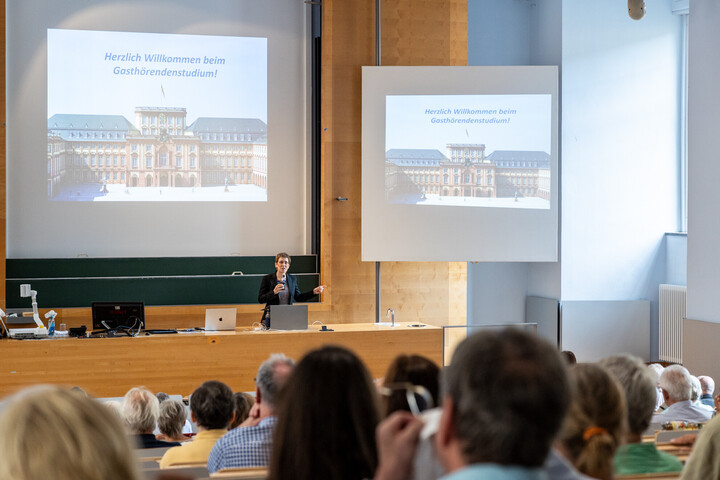 Ein voller Vorlesungssaal, in dem Gasthöhrende zu ihrem Studium begrüßt werden
