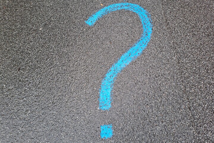 A question mark is drawn on the black asphalt with blue chalk