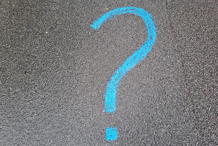 Schwarzer Asphalt auf den mit blauer Kreide ein Fragezeichen gemalt ist
