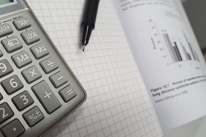 Taschenrechner und Stift, die auf einem aufgeschlagenen Statistikbuch liegen
