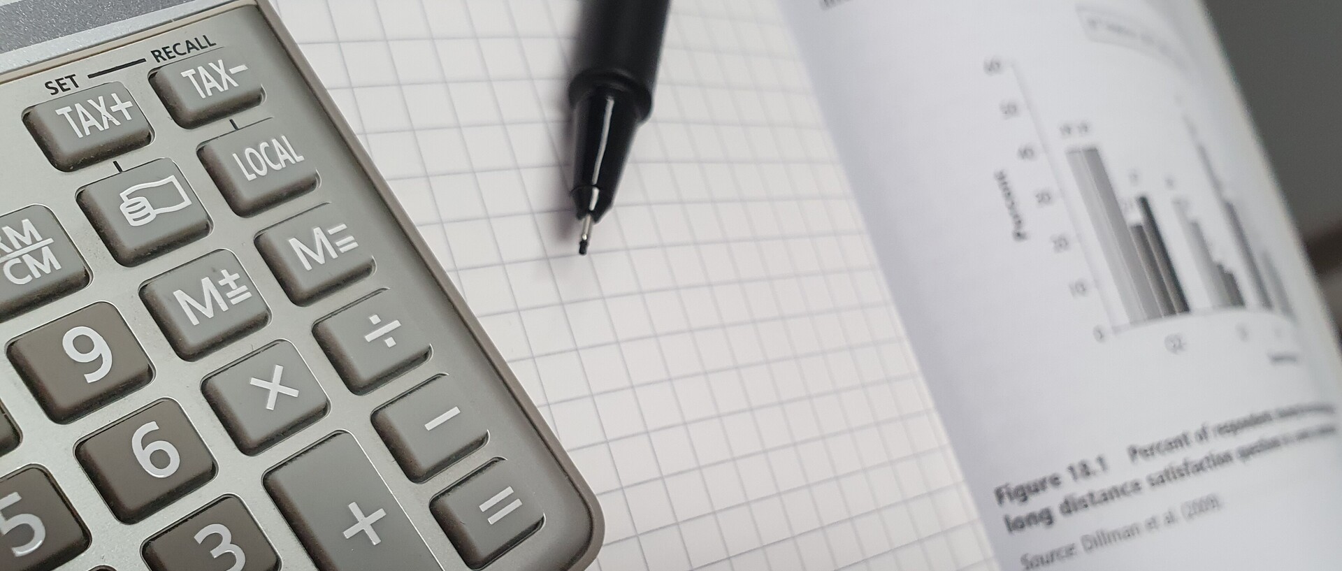 Taschenrechner und Stift, die auf einem Statistikbuch liegen