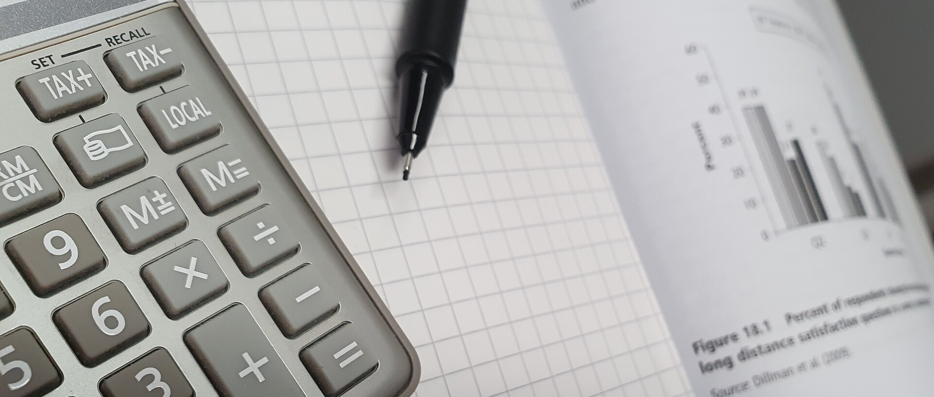 Calculator and pen lying on a statistics book
