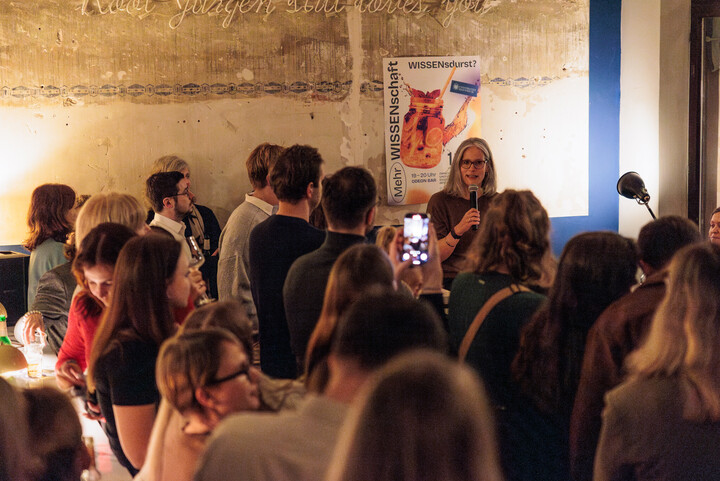Prof. Dr. Jutta Mata hält einen Vortrag in der Odeon Bar. Viele Zuhörer*innen gucken in ihre Richtung.