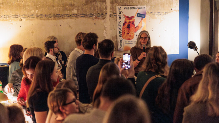 Prof. Dr. Jutta Mata hält einen Vortrag in der Odeon Bar. Viele Zuhörer*innen gucken in ihre Richtung.