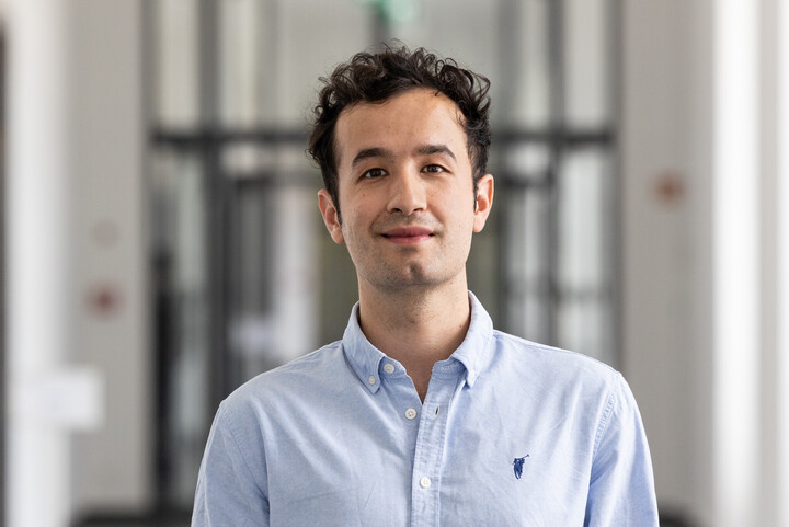 Arkat Erpen trägt ein blaues Hemd und schaut frontal in die Kamera. Er steht in einem Flur im Schloss.