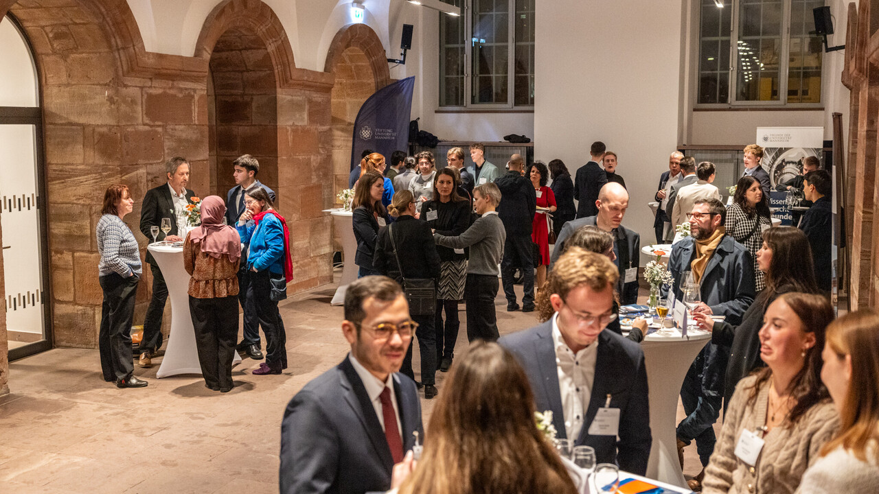 Viele Menschen stehen in einem Raum in Gruppen zusammen und unterhalten sich