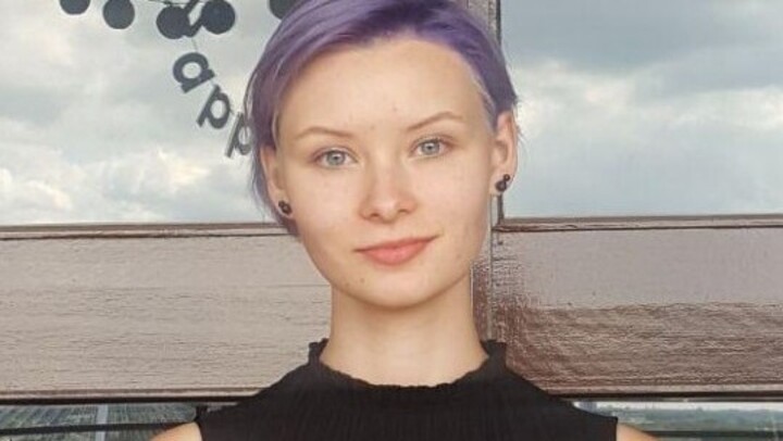 Anna Sokolova. She is wearing a top and is standing in front of a window.