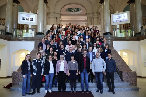 Gruppenbild: Alle Teilnehmenden der Jahrestagung, ca 120 Personen, stehen auf einer Treppe und blicken in die Kamera.