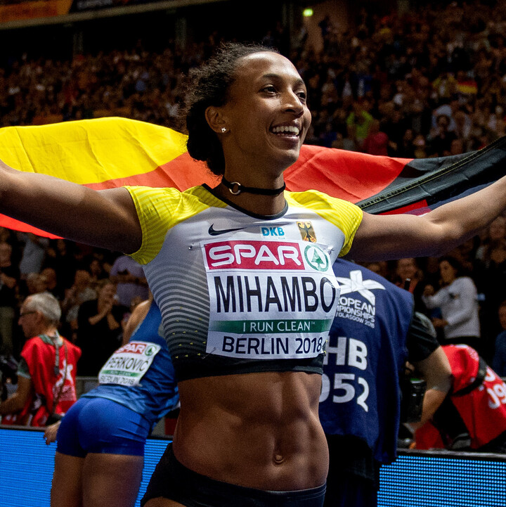 Malaika Mihambo bei der EM: Sie trägt Sportkleidung und hält eine Deutschland-Flagge.