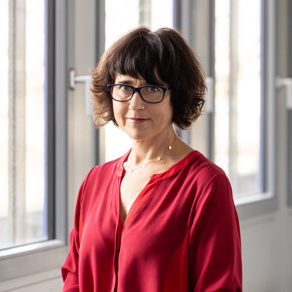 Prof. Kogan trägt ein rotes Oberteil und eine Brille.