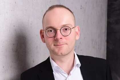 Portraitfoto von Dr. Constantin Wurthmann. Er trägt ein weißes Hemd und ein schwarzes Sakko.