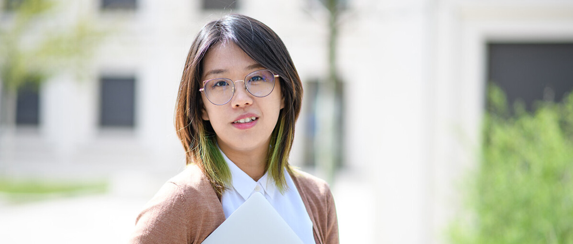 A young woman is smiling and standing in the courtyard of B6, 30-32.